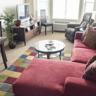 A cozy living room featuring a red sofa, colorful rug, TV, and various furnishings.