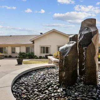 A modern outdoor fountain with large rocks in front of a residential building under a clear sky.