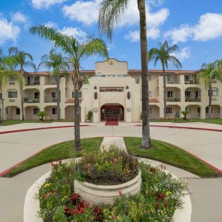 A scenic view of a Mediterranean-style building with palm trees and landscaped surroundings.