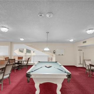 A game room featuring a pool table and seating area on red carpet.