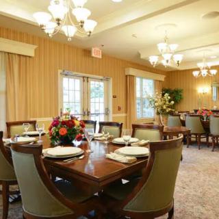 An elegantly set dining room with chandeliers and floral arrangements.
