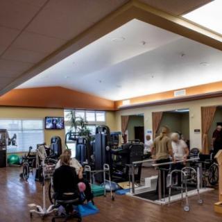A physical therapy center with various exercise equipment and people undergoing rehabilitation exercises.