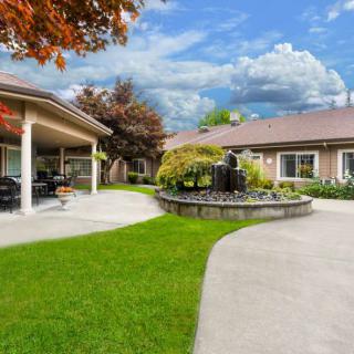 A beautifully landscaped garden with a fountain and patio adjacent to a building.