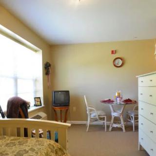 A cozy bedroom with a small dining area, including a table and chairs near the window.
