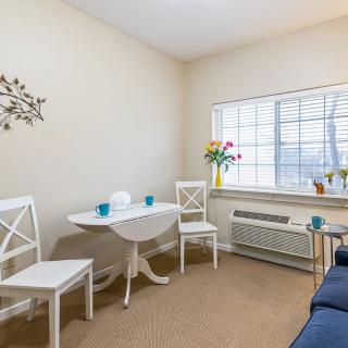 A cozy living room with a small dining table, chairs, and a window with natural light.