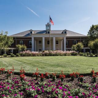 A building with a manicured garden and American flag prominently displayed.