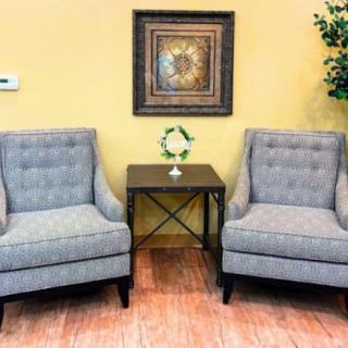 A cozy seating area with two gray armchairs, a small table, and decorative elements in a warmly lit room.