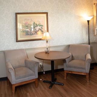 A cozy seating area featuring two armchairs, a small table, and a lamp, perfect for relaxation.