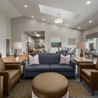 A modern and spacious living room featuring comfortable seating with a sofa and armchairs, a central coffee table, and contemporary lighting.