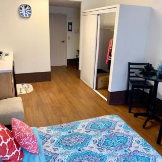 A cozy bedroom with a colorful bedspread, mirrored wardrobe, and a small dining area.