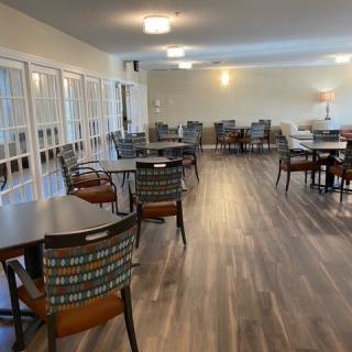 An empty dining area with neatly arranged tables and chairs on a wooden floor.