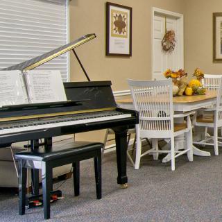 A cozy interior featuring a piano and a dining table with chairs.