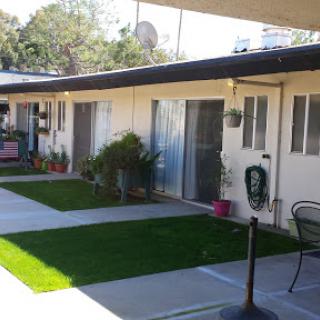 A view of a motel courtyard featuring well-maintained grass and potted plants.