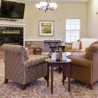 A cozy living room with armchairs, a sofa, and a fireplace, complemented by a television and stylish decor.