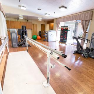 A spacious fitness and rehabilitation room featuring exercise equipment and a ballet barre.