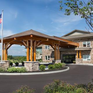 A modern building entrance featuring a wooden canopy and landscaped surroundings.