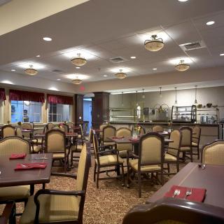 An empty dining room with neatly arranged tables and chairs, featuring elegant lighting and a spacious interior.