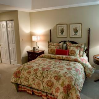A cozy and elegantly decorated bedroom featuring floral bedding and decorative wall art.