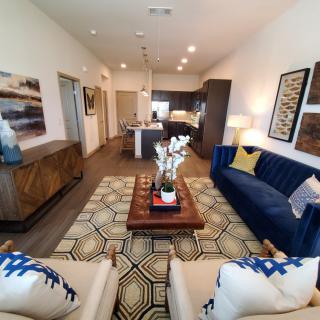 A modern living room with stylish decor, featuring a blue sofa and patterned rug.