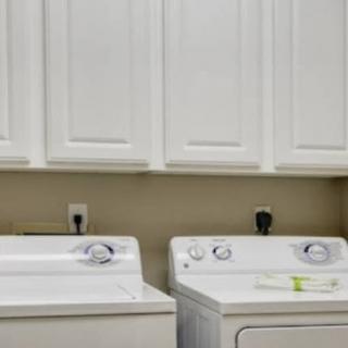 A clean and organized laundry room featuring a washing machine and dryer with white cabinetry above.