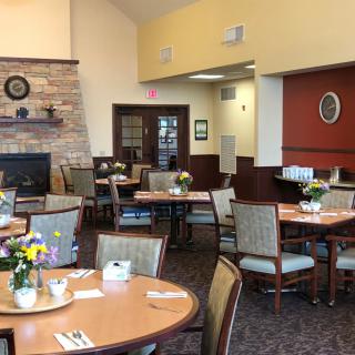A cozy dining area with neatly arranged tables and chairs, decorated with fresh flowers.
