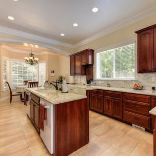 A spacious modern kitchen with wooden cabinets, a granite island, and an adjoining dining area.