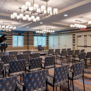 A well-lit conference room with rows of patterned chairs and a grand piano.
