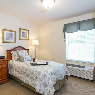 A cozy bedroom with a single bed, nightstand, and window with curtains.
