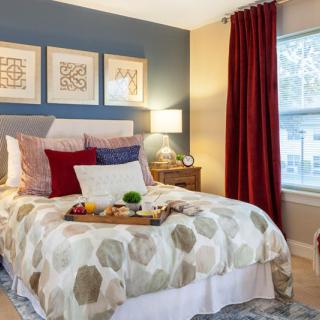 A cozy bedroom with a neatly made bed, colorful pillows, and elegant decor.