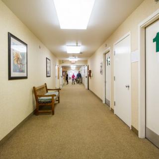 A well-lit hallway with doors on both sides and seating along the wall.