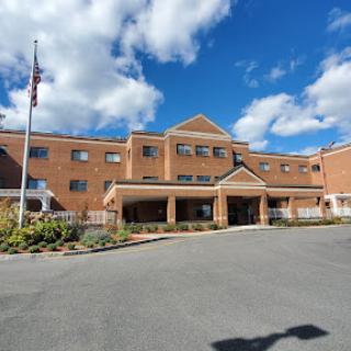 A brick hospital building under a clear blue sky with clouds.