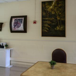 A cozy interior featuring a table and chair, complemented by artwork on the walls.