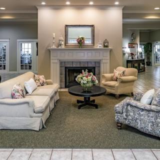 A cozy living room featuring a fireplace, sofas, and a coffee table with floral decorations.