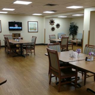 A spacious dining area with tables and chairs, featuring a television on the wall.
