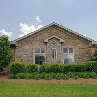 A brick residential house with multiple windows and a well-maintained lawn.
