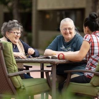 A group of people enjoying a conversation outdoors at a table.
