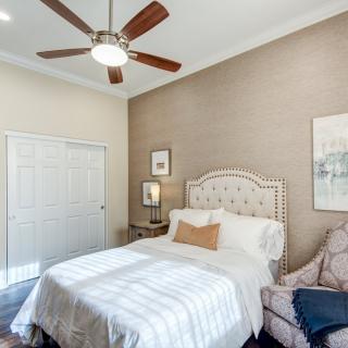 A cozy bedroom featuring a neatly made bed, ceiling fan, and stylish decor.