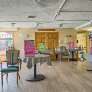 A casual dining area featuring tables and chairs, with colorful decorations in the background.