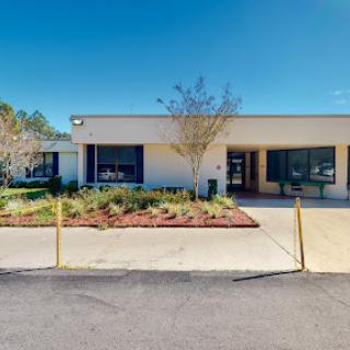 A view of a modern commercial building with landscaped surroundings and a clear blue sky.