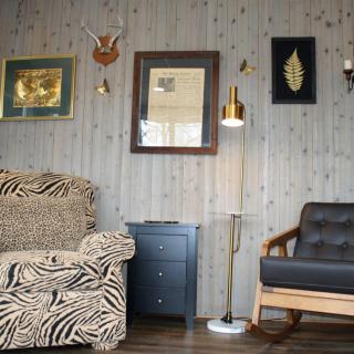 A cozy living room with eclectic decor, featuring a zebra print couch and various wall art pieces on wood paneling.