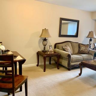 A cozy living room with a sofa, coffee table, side tables with lamps, and a dining area.