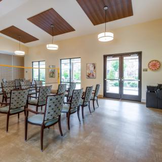 A well-lit meeting room with arranged chairs and large windows.