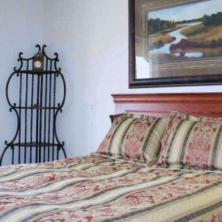 A cozy bedroom with a decorative bedspread and framed artwork on the wall.