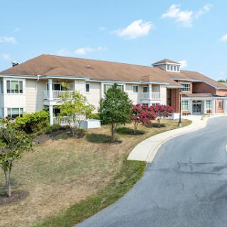A charming residential building nestled among greenery with a winding driveway.