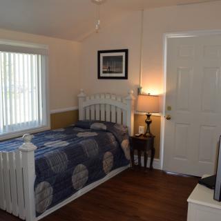 A cozy bedroom with a single bed, lamp, and a window letting in natural light.