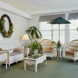 A cozy living room with white furniture, decorative plants, and a wreath on the wall.