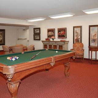 A cozy game room featuring a classic pool table surrounded by comfortable seating and decorative artwork.