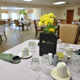 A beautifully set table in a dining room with yellow flowers as a centerpiece.