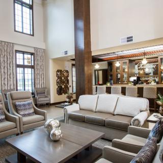 A modern living room with a high ceiling, featuring cozy seating and stylish decor.