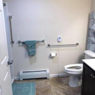 An accessible bathroom featuring grab bars, a towel rack, and a toilet.